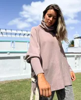 Polerón de cuello alto y corte oversize, color rosado, con mangas largas de puño acanalado y detalle de ojalillos metálicos con tiras en los laterales.