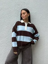 Sweater tipo chomba de tejido bremer con diseño de rayas horizontales en color marrón y celeste. Presenta cuello polo en color crema con cierre frontal de botones y mangas largas.