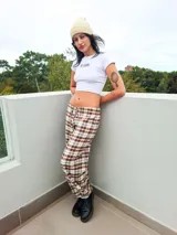 Pantalón de corte holgado con estampado de cuadros en tonos marrones y blancos. Presenta cintura elástica con cordón ajustable y puños elásticos en los tobillos.