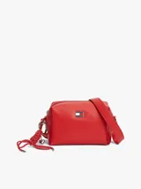 Bandolera Tommy Jeans de color rojo, diseño estructurado de silueta cuadrada con acabado liso. Cuenta con cierre de cremallera, correa ajustable y un colgante lateral de cordón trenzado con adorno en forma de corazón. Incluye la insignia con el logo de la marca en la parte delantera.