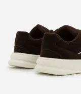 Championes de estilo skater para hombre, confeccionados en poliuretano color marrón oscuro. Poseen punta redonda, caña baja y suela de plataforma blanca. Destacan por sus cordones anchos tipo fat lace y detalles laterales en contraste.
