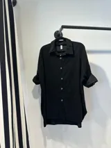 Camisa negra de pana con bordados florales a tono, corte oversize y ruedo curvo.