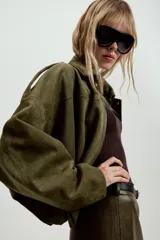 Chaqueta de efecto ante color marrón claro, con cuello solapa, manga larga con trabillas en los hombros y bajo abullonado. Cierre frontal con cremallera y botones ocultos por solapa.