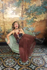 Vestido largo de encaje y transparencias color marrón, con escote profundo halter, frunces en el cuerpo, espalda abierta y tiras largas estampadas para atar al cuello.
