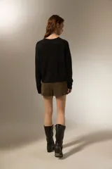 Sweater de punto negro con destellos de lurex, cuello redondo a la base y mangas largas con puños ajustados.