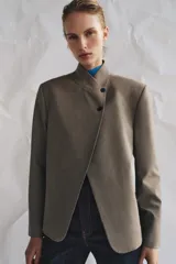 Blazer de cuello subido con cierre frontal cruzado de botones. Presenta manga larga con hombreras y puños con botones, bolsillos de vivo en el delantero y forro interior.