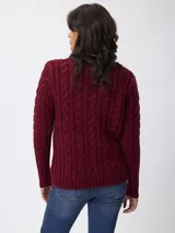 Sweater de tejido grueso con textura trenzada, cuello alto y mangas largas.