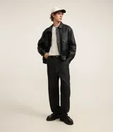 Campera masculina estilo boxy de poliuretano color negro, con cuello camisero, cierre frontal oculto con botones, bolsillos plaqué con solapa en el pecho y ajuste elastizado en el bajo.