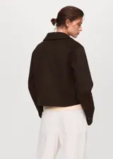 Chaqueta de corte recto confeccionada en mezcla de lana, con cuello camisero, cierre frontal de botones y dos bolsillos de solapa en el frente.