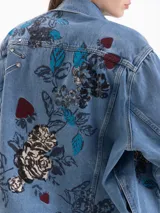 Chaqueta de denim de corte oversize con diseño de bordados y estampas exclusivas. Posee cuello clásico, cierre frontal con botones metálicos y bolsillos con solapa en el pecho.