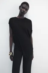 Top de punto color negro, con cuello redondo, manga corta y diseño asimétrico de corte fluido y caída en punta.