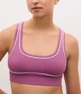 Top deportivo de microfibra con diseño de espalda nadador, escote en U y breteles anchos. Presenta detalles de frisos blancos en contraste y cuenta con copas desmontables.