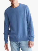 Sweater de punto color azul melange, con cuello redondo, manga larga y acabados acanalados en puños y bajo. Presenta un pequeño logo bordado en el pecho.