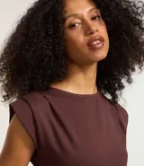 Top ajustado color rojo, con cuello redondo y mangas cortas tipo hombreras o almohadillas. El tejido parece ser de punto o viscosa con buena caída y presenta un fruncido horizontal a la altura de la cintura.