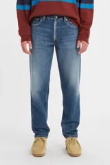 Jean de corte relajado y pierna cónica, con tiro medio y cierre de botones. Presenta un lavado azul medio con efecto desgastado.