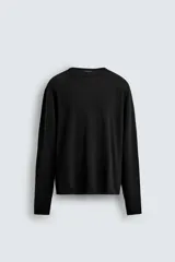 Jersey de manga larga, cuello redondo y calce relajado, color negro con efecto lavado y textura tejida.