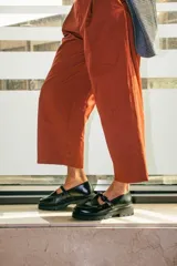 Mocasines estilo Mary Jane con diseño de estampado de vaca (cow print), confeccionados en cuero. Presentan una tira con hebilla ajustable sobre el empeine y una suela track negra de 4,5 cm de altura.