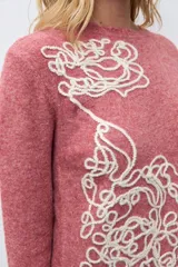 Sweater de punto color rojo melange, con cuello redondo, manga larga y detalle de bordado floral en relieve en color crudo en el frente.