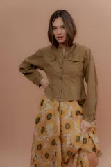 Chaqueta verde militar de corte clásico, cuello mao y cierre frontal con botones. Cuenta con bolsillos ojal en el pecho y mangas largas.
