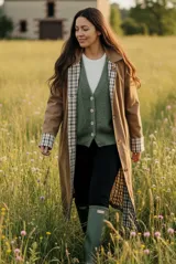 Trench reversible de corte clásico con cinturón ajustable. Un lado presenta un diseño liso en color verde militar, mientras que el reverso cuenta con un estampado a cuadros en tonos neutros. Posee cierre frontal con botones y cuello camisero.