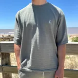 Remera verde oliva de tejido texturizado con logo bordado en el pecho.