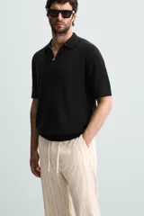 Polo de manga corta, color azul medio, tejido en punto perlado con cuello solapa y cierre frontal de cremallera.