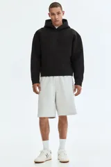 Canguro negro con capucha de doble capa, efecto neopreno, hombros caídos, bolsillo canguro frontal y puños y bajo anchos acanalados. Corte holgado.