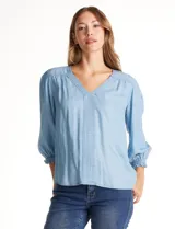 Blusa Zac & Rachel de lyocell color azul, con escote en V y panel central con pespuntes. Presenta mangas tres cuartos abullonadas con frunces en los hombros y puños elastizados con detalle de volante.