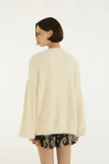 Sweater de tejido de punto con acabado afelpado, cuello redondo y mangas largas de volumen amplio. Diseño liso en color beige con silueta relajada.