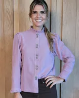 Camisa de manga larga con estampado de rayas verticales en tonos crudo y beige. Presenta cuello alto con volados, cierre frontal con botones dobles y puños con volados.