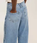 Pantalón de jeans celeste marmolado, corte barrel, con trabillas en la cintura, bolsillos delanteros y traseros, y detalle de recortes en las rodillas.