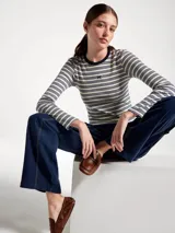 Camiseta de manga larga con cuello redondo, confeccionada en tejido acanalado con diseño de rayas horizontales en tonos claros y bordó. Presenta un pequeño bordado decorativo en el centro del pecho.