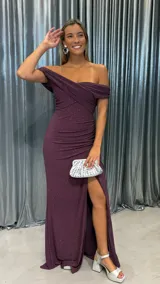 Vestido largo de fiesta color bordó con acabado brillante, diseño de escote cruzado con hombros descubiertos, detalle de frunces laterales y tajo profundo en la pierna.