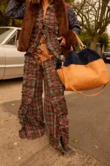 Pantalón de corte amplio con estampado a cuadros, presenta detalles de volados laterales con cordones entrecruzados que aportan textura y movimiento. Incluye bolsillos delanteros y traseros.