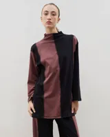 Polera de algodón con diseño bicolor en paneles verticales negros y bordó, cuello alto y tajos laterales.