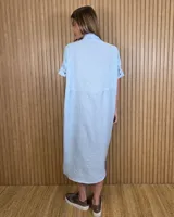 Vestido midi estilo túnica color celeste con rayas verticales blancas, cuello camisero, mangas cortas y cierre frontal con botones ocultos.
