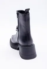 Botas negras de símil cuero, caña corta, punta redonda, plataforma tipo tractor de 6cm de alto y aplique de cadena plateada en el frente.