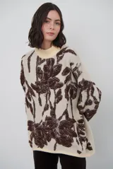 Buzo de tejido de punto con diseño floral en contraste, cuello redondo y mangas largas. Presenta una textura suave y un corte holgado.