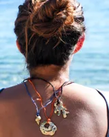 Collar con dije de bronce macizo con forma orgánica irregular, similar a un coral, suspendido de un cordón negro de seda natural anudado.