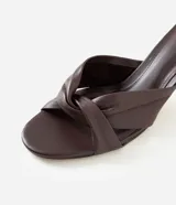 Sandalia mule Satinato de cuero marrón oscuro, con detalle de nudo frontal, taco kitten fino y puntera abierta.