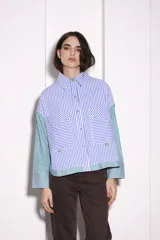 Camisa corta con cuerpo a rayas verticales azules y blancas, mangas a rayas verticales verdes y blancas, cuello camisero y cierre frontal con botones dorados.