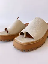 Sandalias de cuero crudo con tira ancha sobre los dedos y suela track color caramelo.