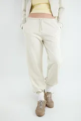 Pantalón jogger color beige, confeccionado en mezcla de algodón y poliéster, con cintura elástica ajustable mediante cordón y puños elásticos en los tobillos.