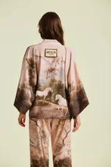 Kimono de mujer con silueta amplia y envolvente, mangas murciélago y lazo para ajustar en la cintura. Presenta un estampado de paisaje editorial con caballos.