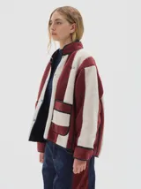 Campera de sherpa con diseño de rayas verticales en color bordó y crema. Presenta cuello alto, cierre frontal con broches a presión, mangas largas y bolsillos frontales aplicados con vivos a contratono.
