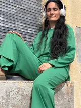Pantalón tipo palazzo de tiro alto, confeccionado en jersey de algodón color verde. Presenta un diseño amplio con bolsillos laterales y una faja ancha en la cintura que proporciona ajuste y soporte.
