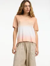 Remera de punto color durazno con degradé blanco en el centro, escote en V y mangas cortas.