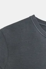 Camiseta de corte entallado confeccionada en mezcla de algodón, con cuello redondo y mangas cortas. Presenta un diseño básico de bajo recto en color gris oscuro.