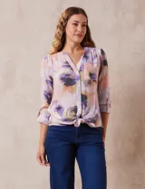 Blusa estampada de Zac & Rachel con cuello a la base, escote en V y botones. Tiene un bolsillo aplicado en la parte delantera, mangas largas regulables con presilla y botón, y terminación anudada opcional.