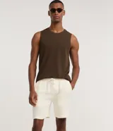 Bermuda de hombre color blanco crudo, confeccionada en algodón texturizado. Presenta un corte comfort, cintura elástica con lazo ajustable y bolsillos laterales.